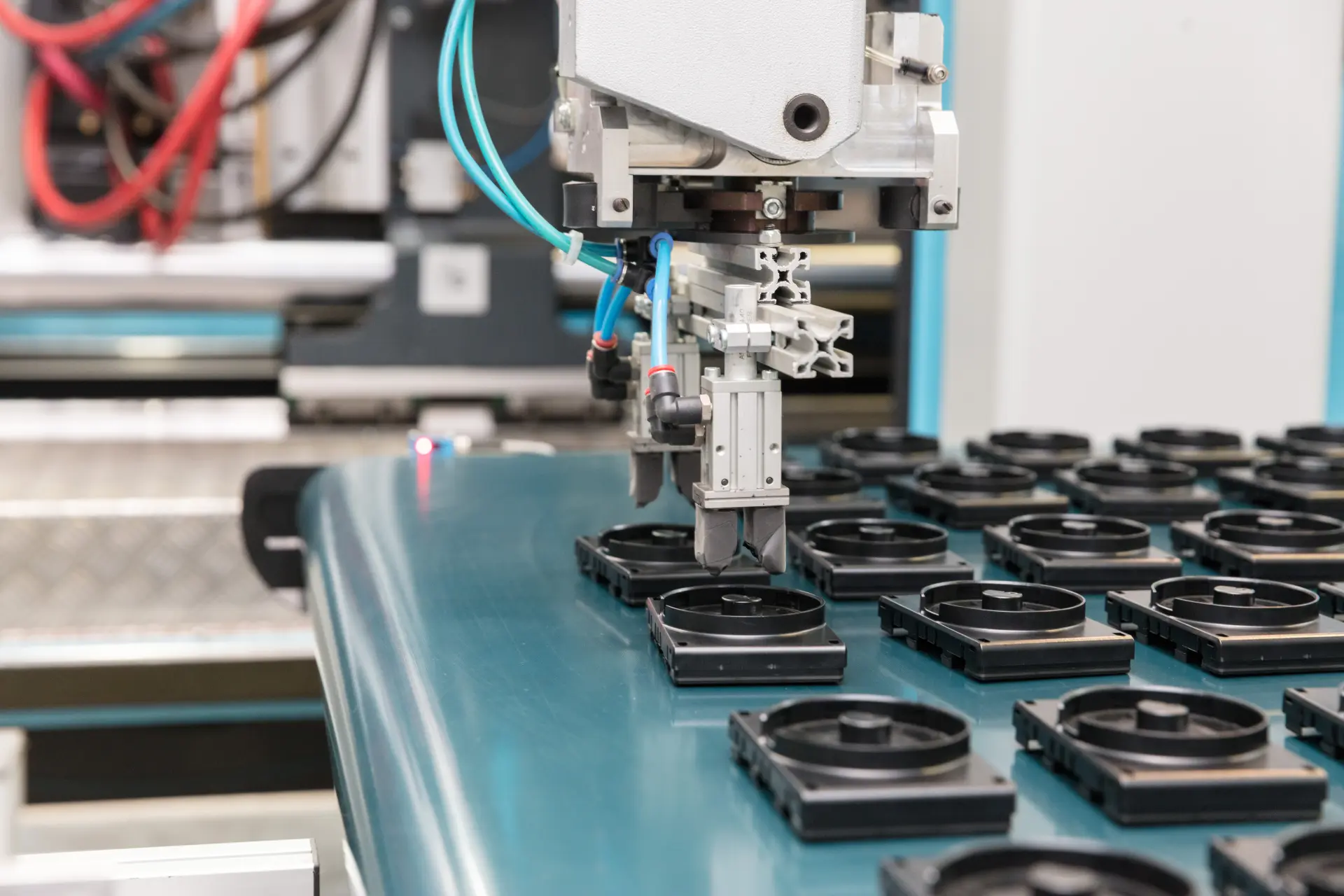 Roboter-Greifer platziert schwarze Kunststoffteile auf einem Förderband.